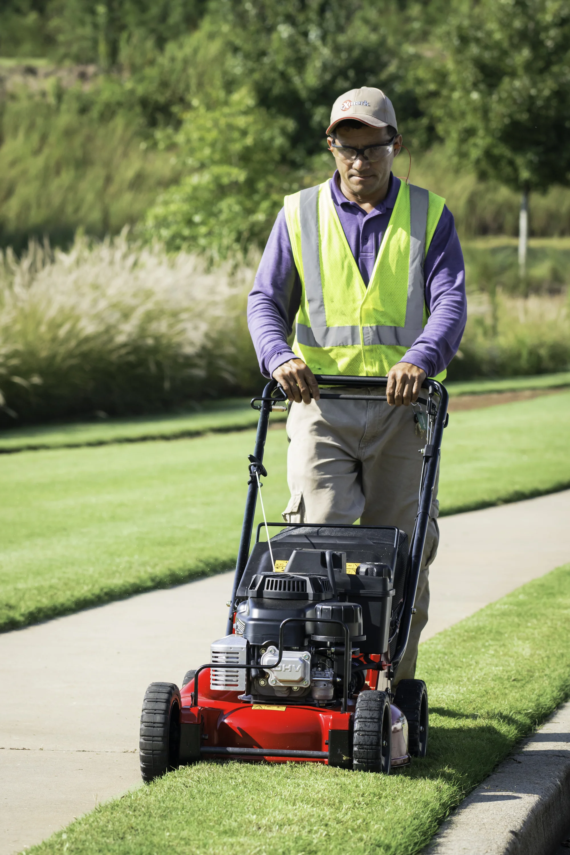 Exmark Commercial 21 X Series Walk Behind Lawn Mower ECX180GKA21000 Exmark Commercial 21 X Series Walk Behind Lawn Mower Ecx180Gka21000 Front View Closeup Man Cutting Grass product image