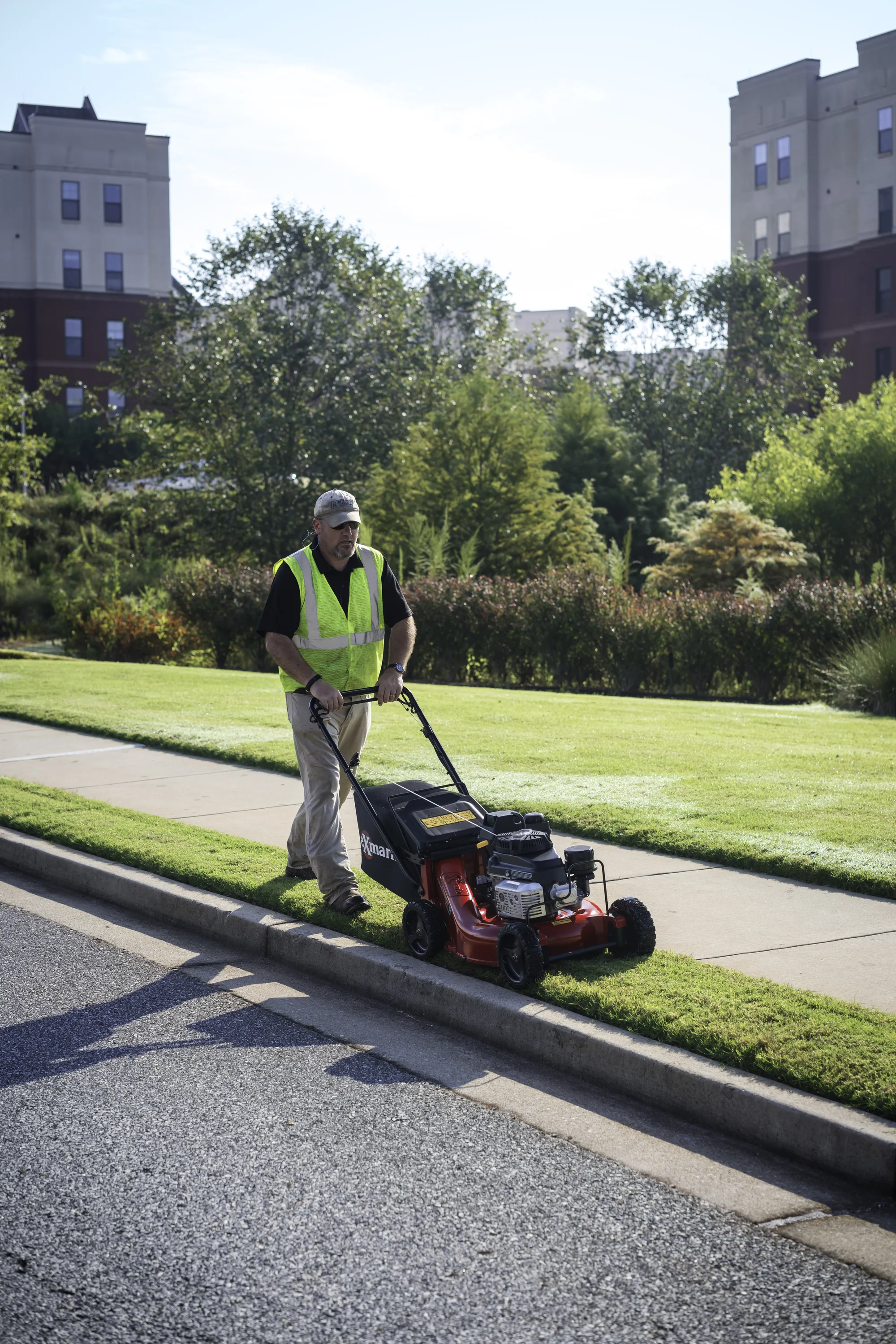 Exmark Commercial 21 X Series Walk Behind Lawn Mower Ecx180Gka21000 Front View Right Man Cutting Grass product image