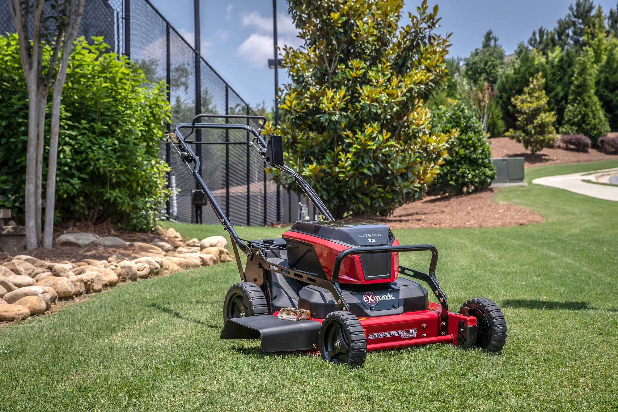 Exmark Commercial 30 V Series Walk Behind Lawn Mower ECV060B0230010 Exmark Commercial 30 V Series Walk Behind Lawn Mower Ecv060B0230010 Left Front Angle Near Rock Border And Fence product image