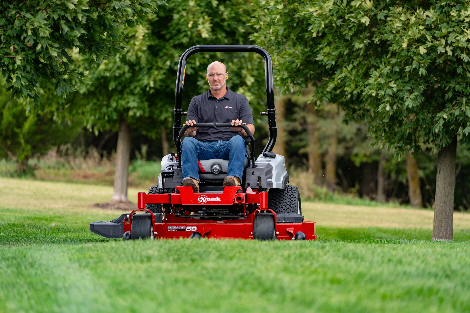 Exmark Radius X Series Zero Turn Rider RDX691GKA524A3 Exmark Radius X Series Zero Turn Rider Rdx691Gka524A3 Man On Mower Forest Front View product image