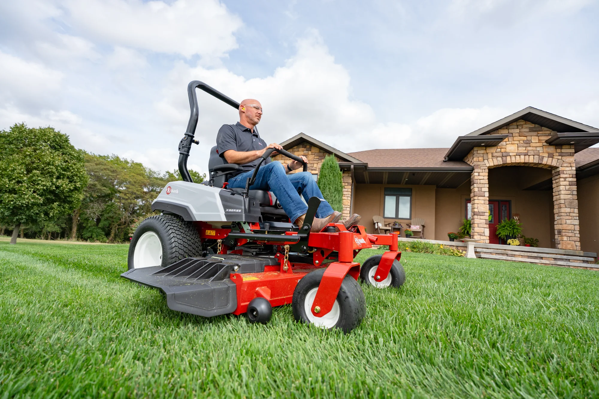 Exmark Radius X Series Zero Turn Rider RDX691GKA524A3 Exmark Radius X Series Zero Turn Rider Rdx691Gka524A3 Man On Mower House Wide Angle product image