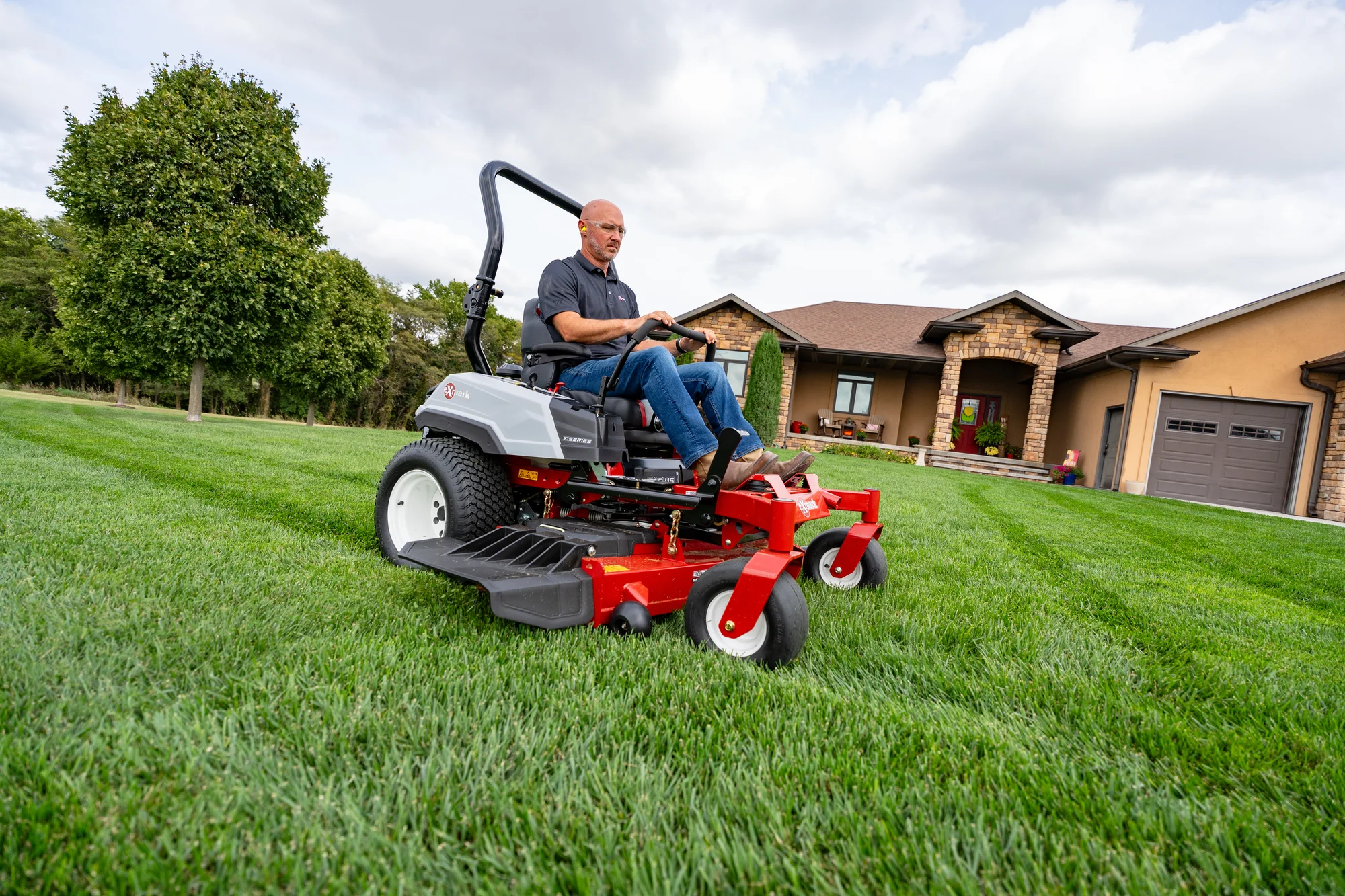 Exmark Radius X Series Zero Turn Rider RDX691GKA524A3 Exmark Radius X Series Zero Turn Rider Rdx691Gka524A3 Man On Mower House Wide Angle Distant product image