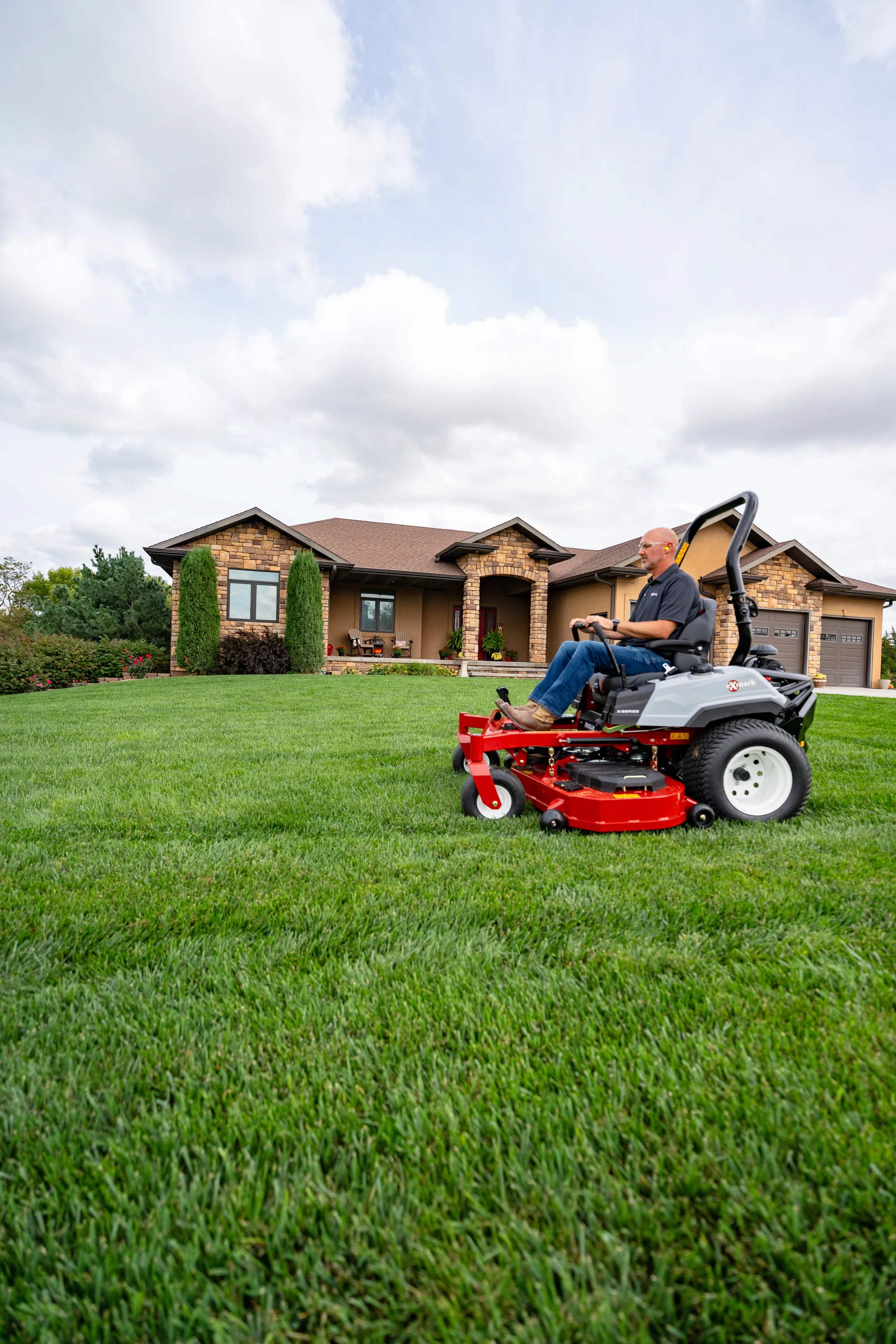 Exmark Radius X Series Zero Turn Rider RDX730GKA604A3 Exmark Radius X Series Zero Turn Rider Rdx730Gka604A3 Man On Mower House Side View product image