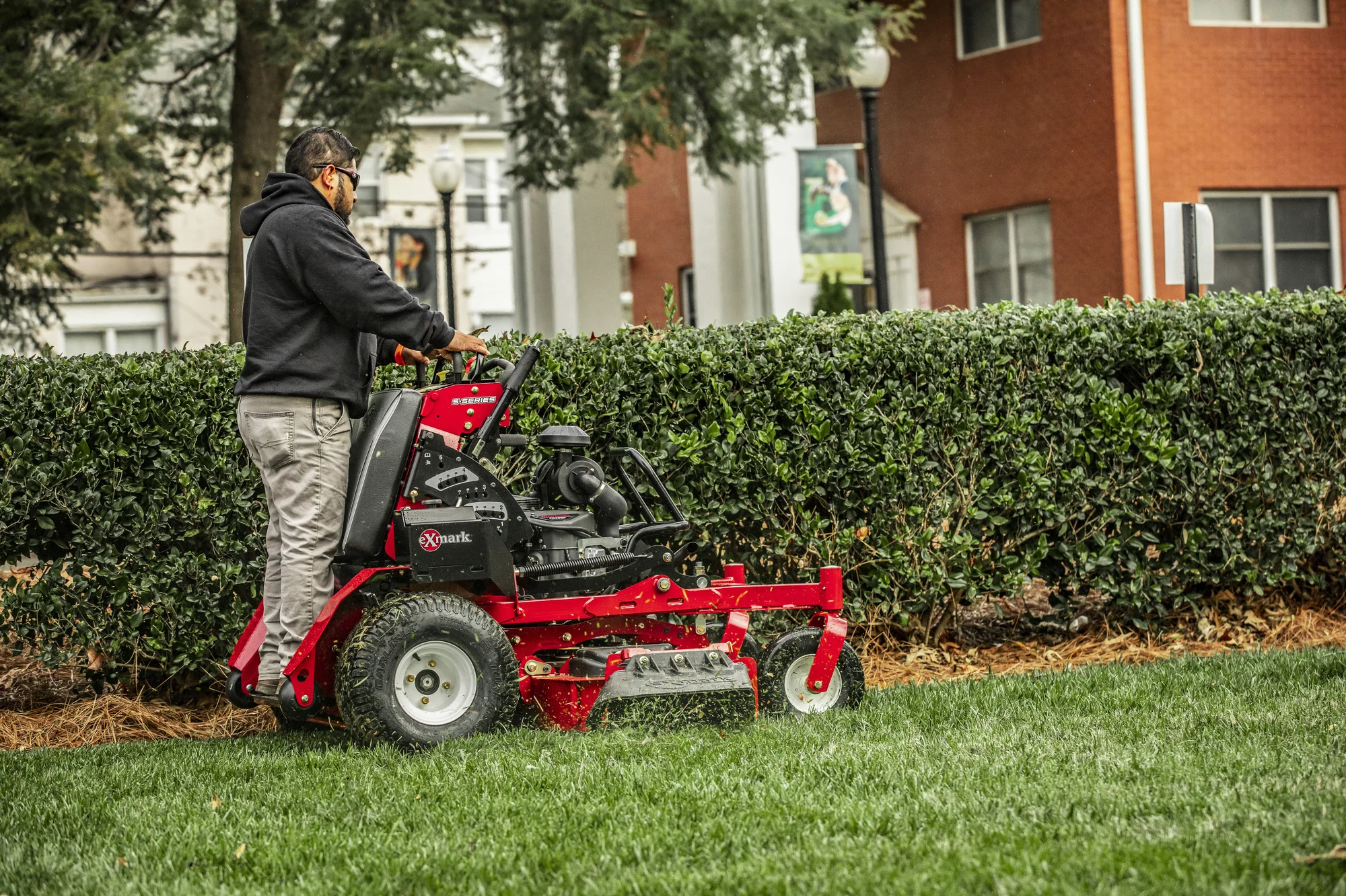 Exmark Vertex S Series Stand On Lawn Mower Vxs730Gka48400 Man Mowing Near Hedges product image