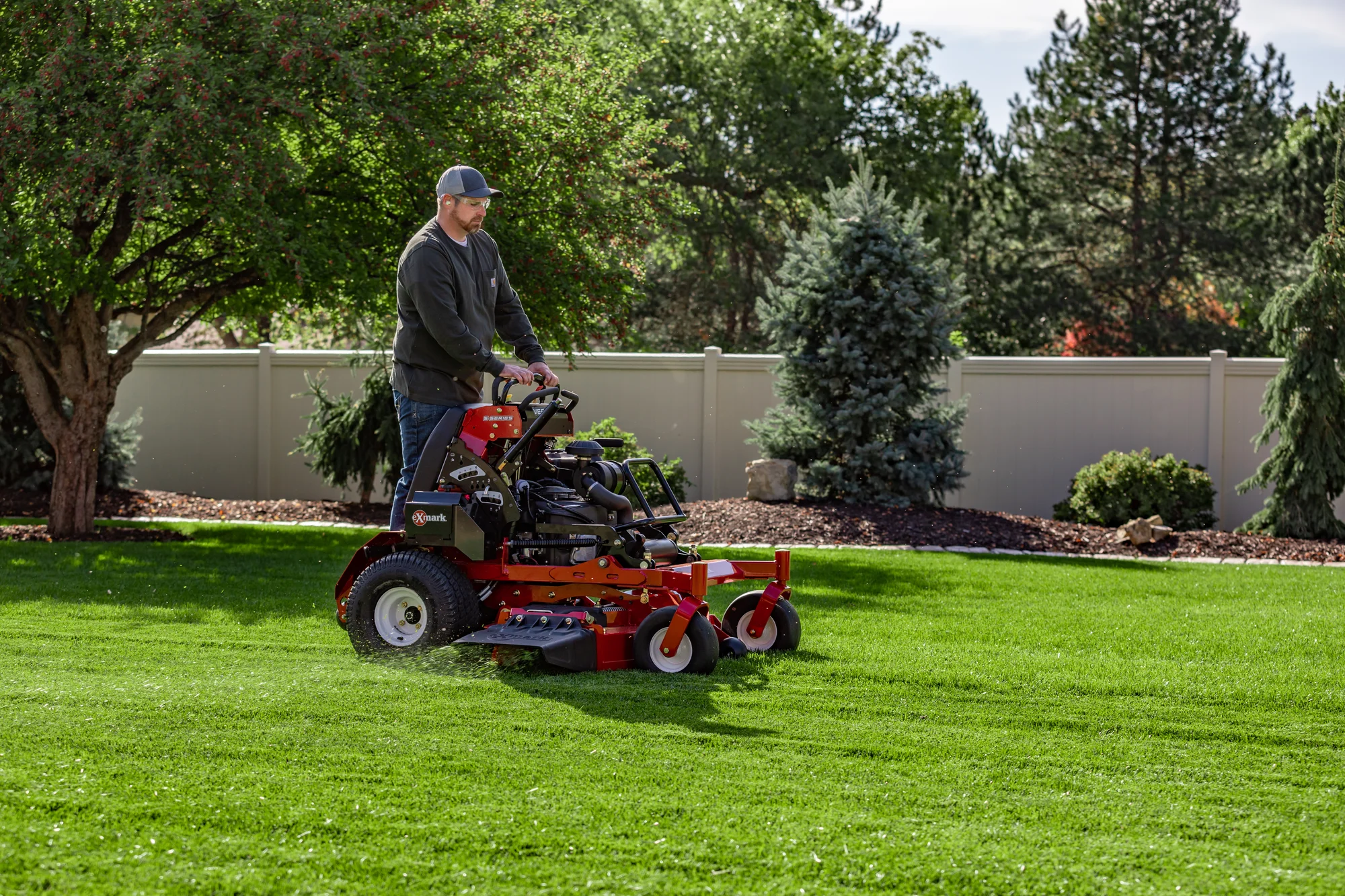 Exmark Vertex S Series Stand-On Lawn Mower VXS740EKC60400 Exmark Vertex S Series Stand On Lawn Mower Vxs740Ekc60400 Man Mowing Lawn Distant product image