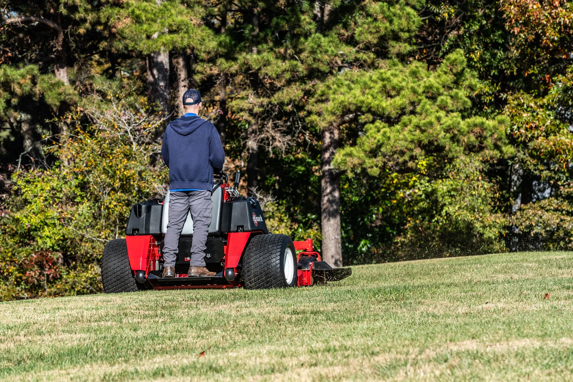 Exmark Vertex X Series Stand On Lawn Mower Vxx999Eka52600 Back View Man Mowing Property product image