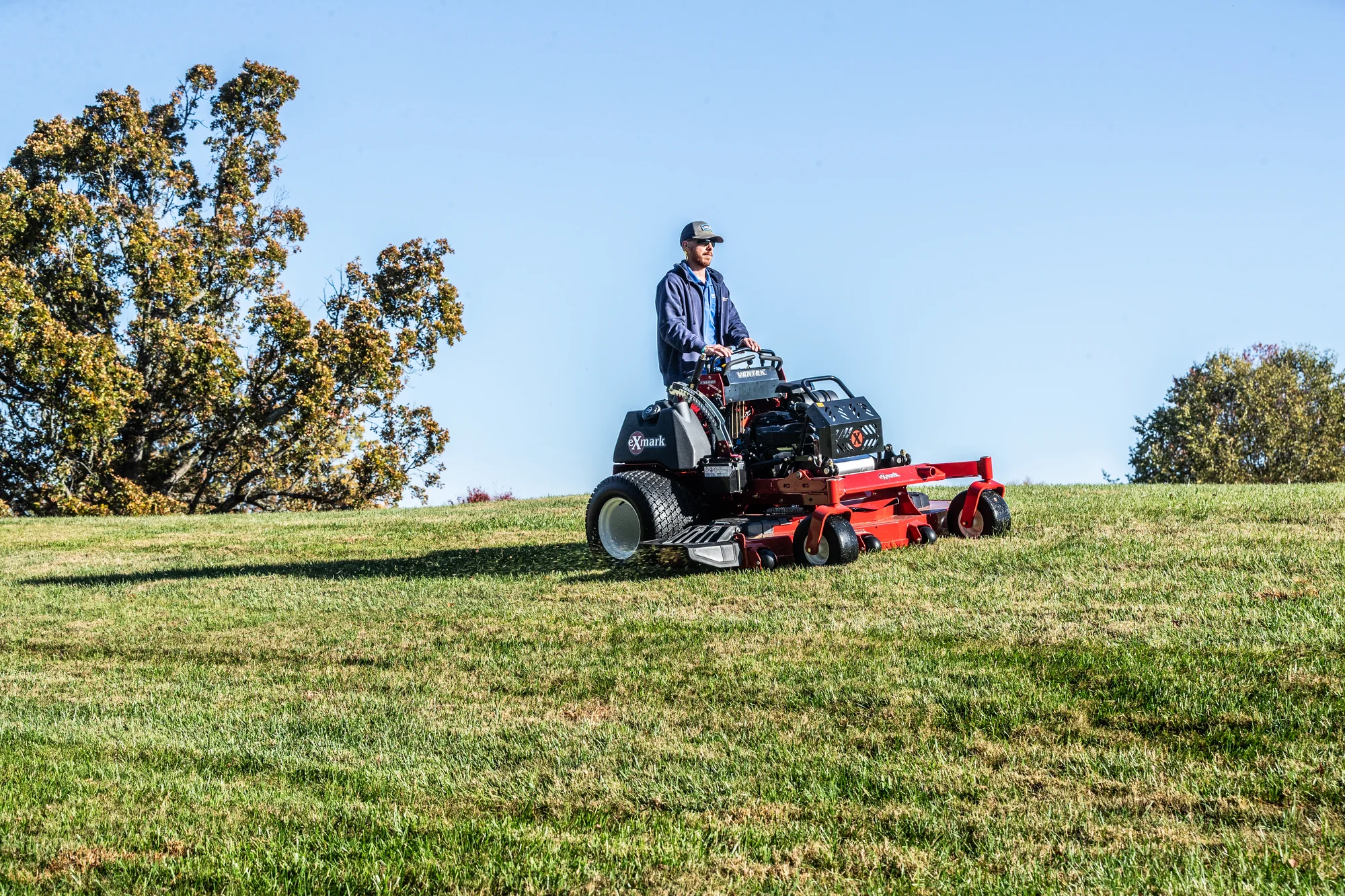 Exmark Vertex X Series Stand-On Lawn Mower VXX999EKA52600 Exmark Vertex X Series Stand On Lawn Mower Vxx999Eka52600 Man Mowing Top Of Hill product image