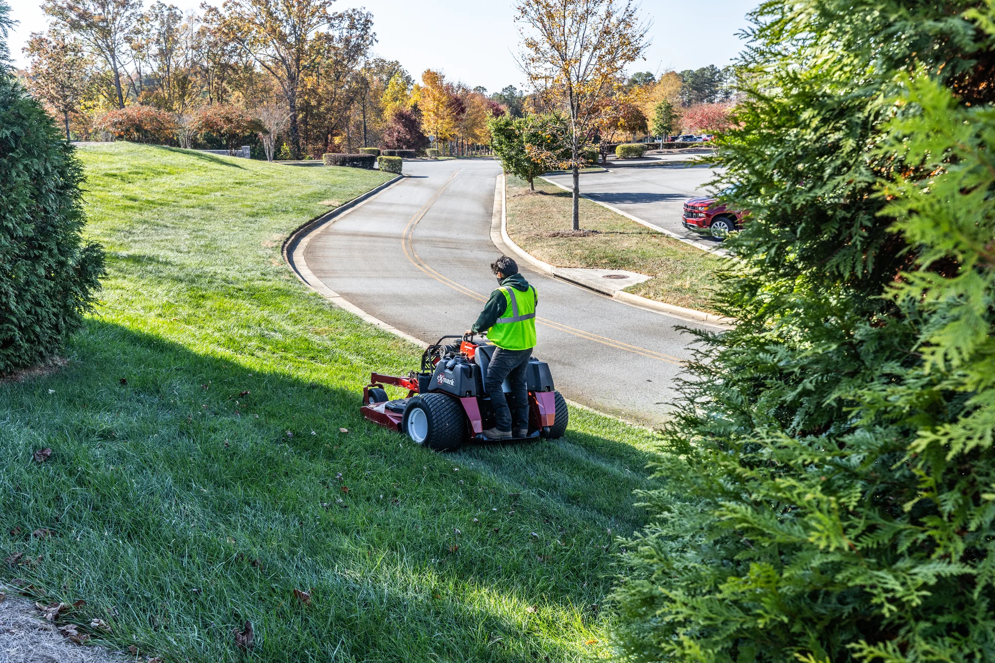 Exmark Vertex X Series Stand-On Lawn Mower VXX999EKA60600 Exmark Vertex X Series Stand On Lawn Mower Vxx999Eka60600 Man With Mask Mowing Hill Distant product image