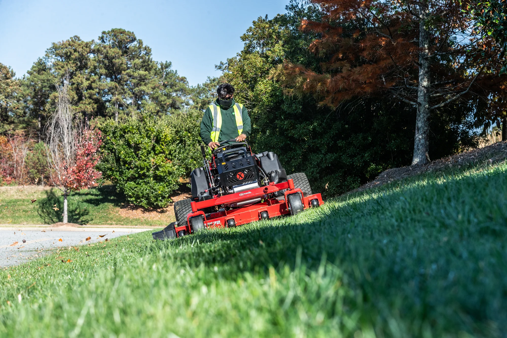 Exmark Vertex X Series Stand On Lawn Mower Vxx999Eka72600 Front View Man With Mask Mowing Hill product image