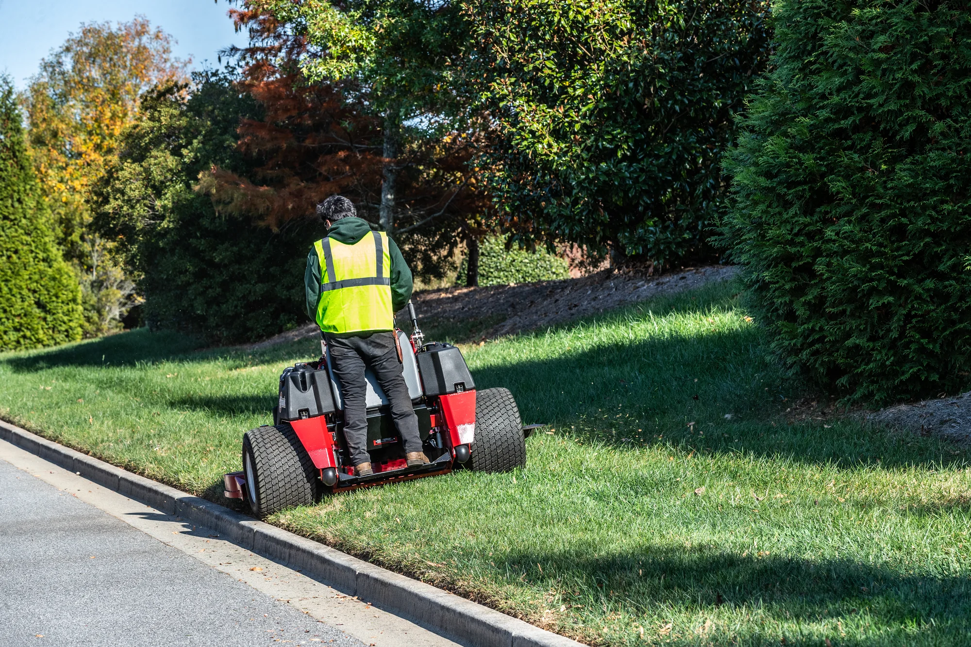 Exmark Vertex X Series Stand-On Lawn Mower VXX999GKA72600 Exmark Vertex X Series Stand On Lawn Mower Vxx999Gka72600 Back View Man With Mask Mowing Near Road product image