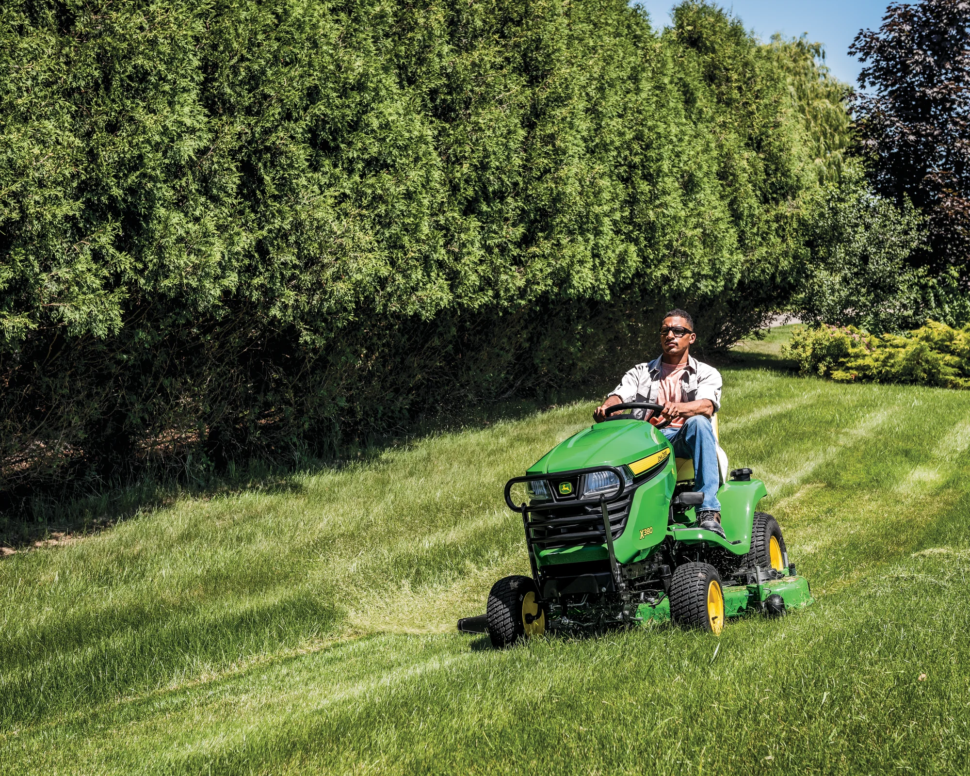 John Deere Select X300 Series Garden Tractor X380 54 Front View Right Wide Man Mowing Lawn product image