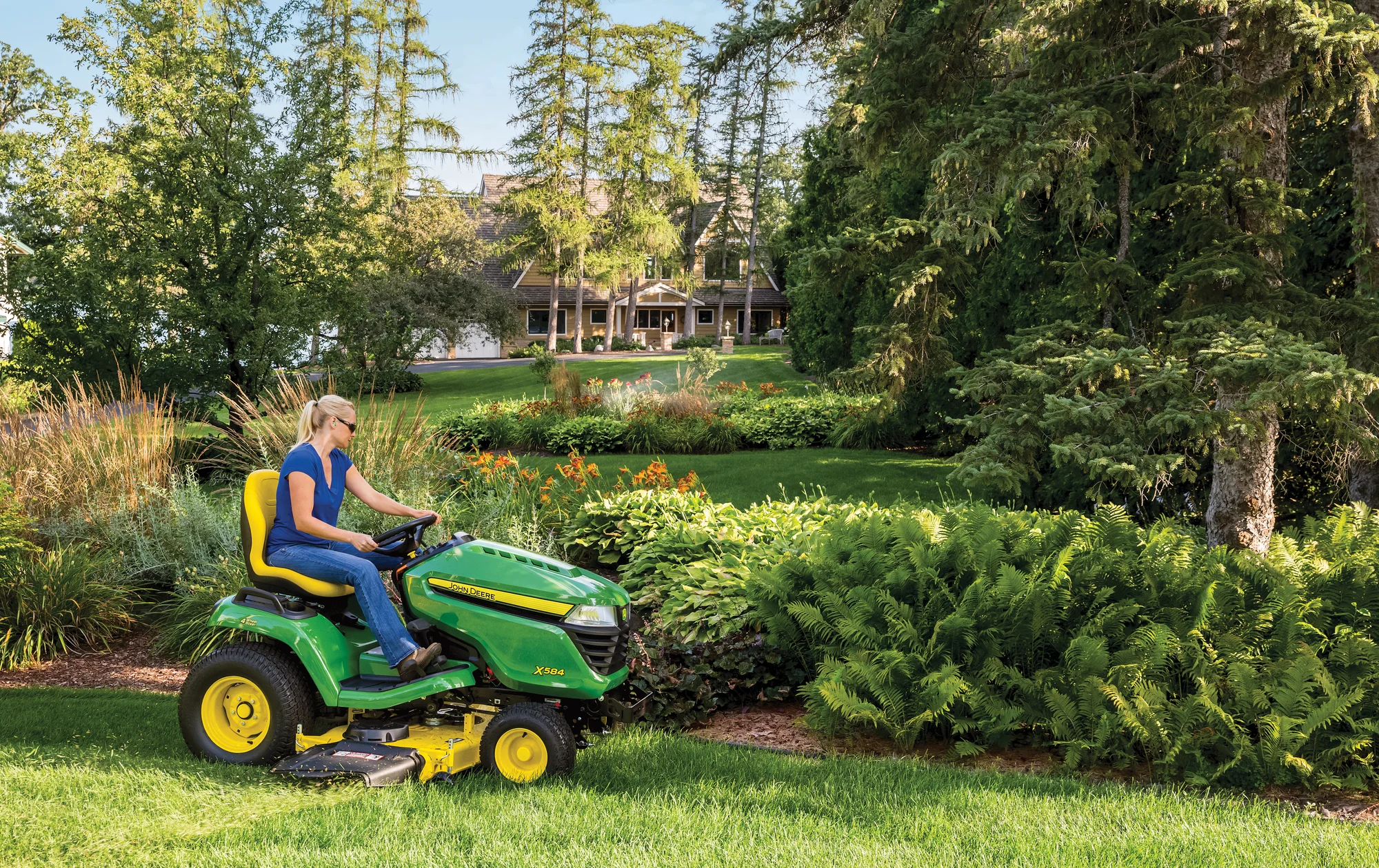 John Deere Select X500 Series Garden Tractor X584 John Deere X500 Select Series Lawn Tractor X584 Women Mowing Around Garden Bed product image