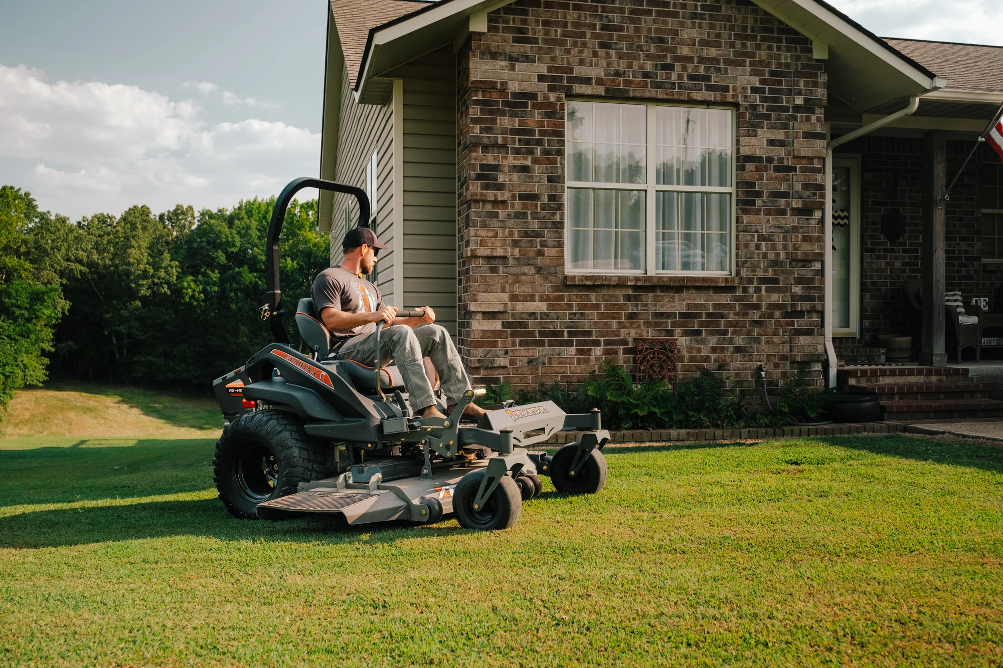 Spartan RZ-HD Zero Turn Rider RSZL1154FR730 Spartan Rz Hd Zero Turn Rider Rszl1154Fr730 Man Cutting Grass House Side View product image