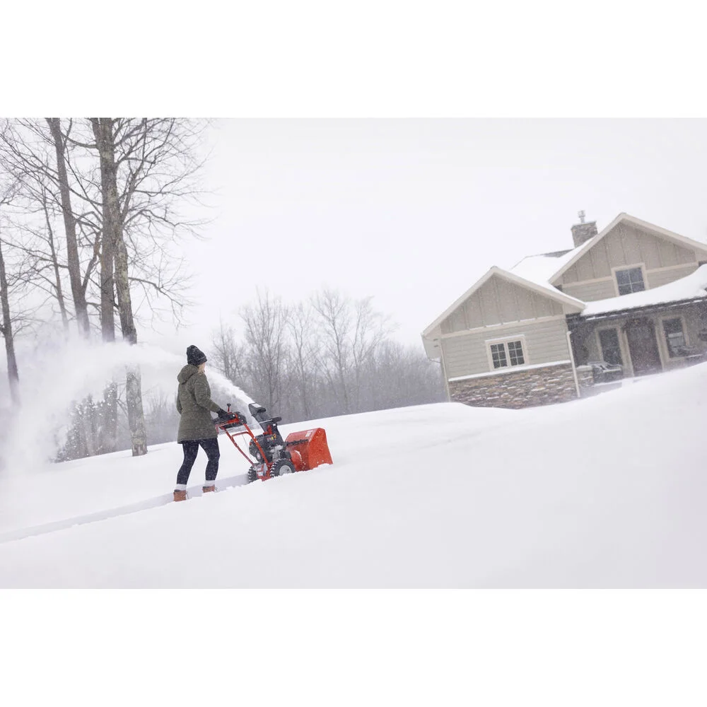 Troy Bilt Two Stage Snow Blower Storm 2420 2X 23 Woman Throwing Snow Distant product image